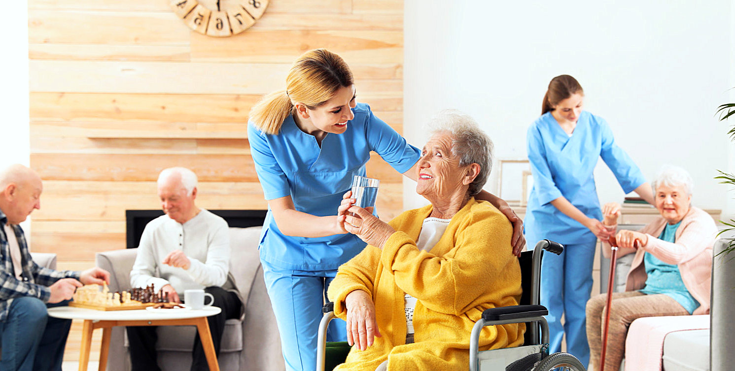 caregivers serving senior women while senior men playing chess