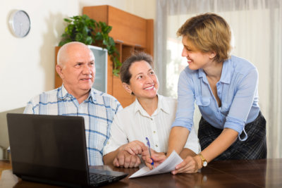 Smiling senior couple answer questions of social worker at home. Focus on woman