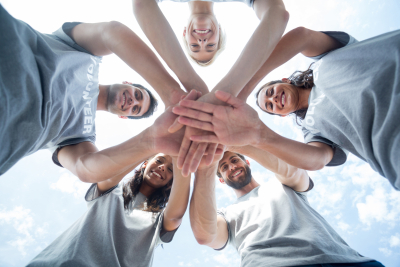 Low angle of happy volunteers putting theirs hands together