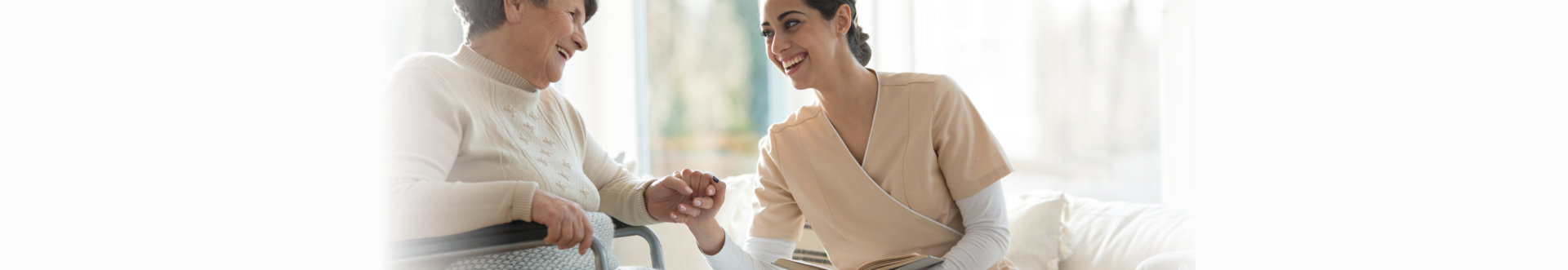 Smiling caregiver taking care of a happy, disabled, elderly woman