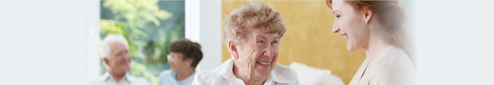 Happy senior woman talking with friendly nurse at geriatric ward